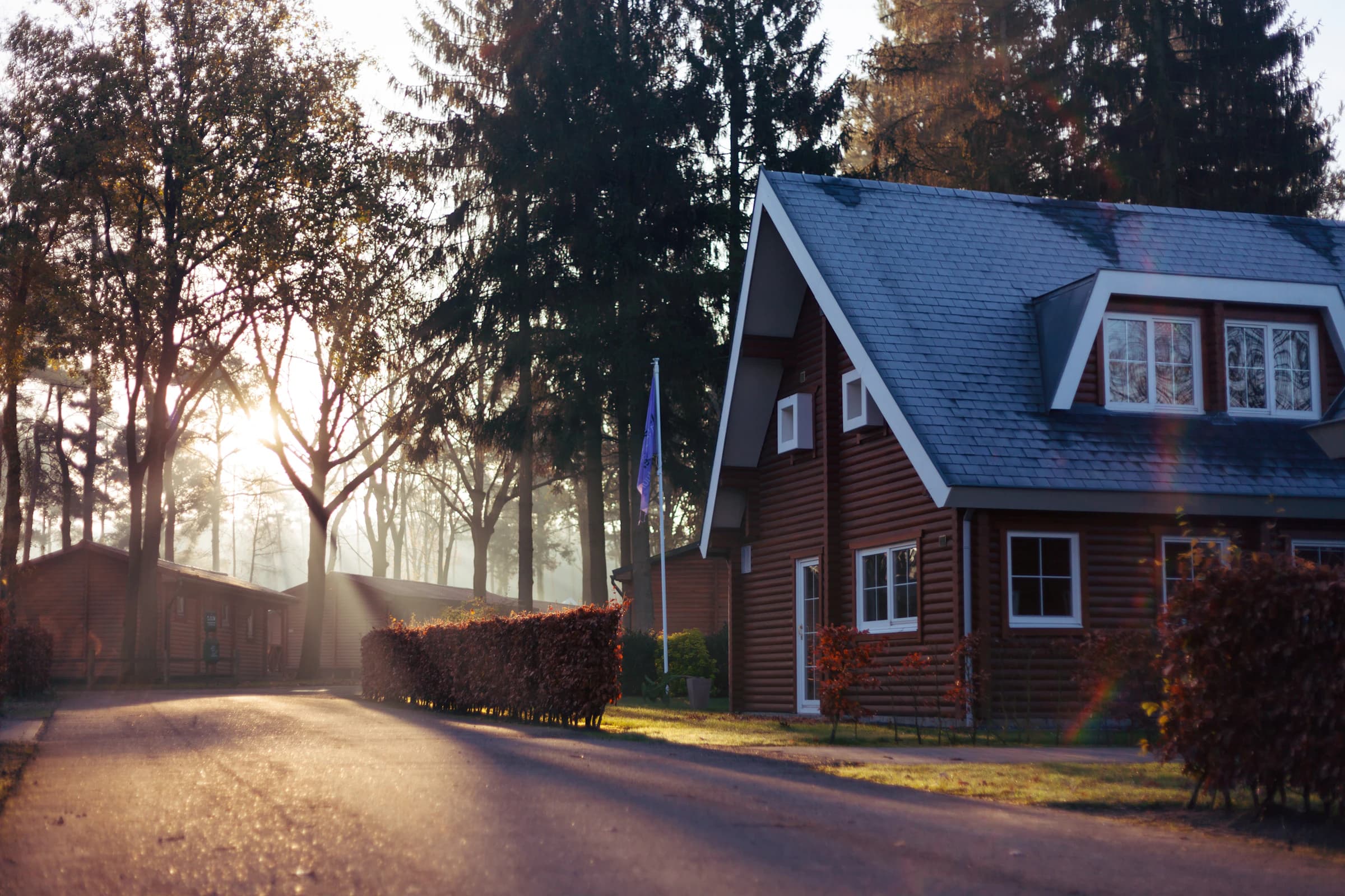 Wood house with tilted roof, low fence and green lawn in light day