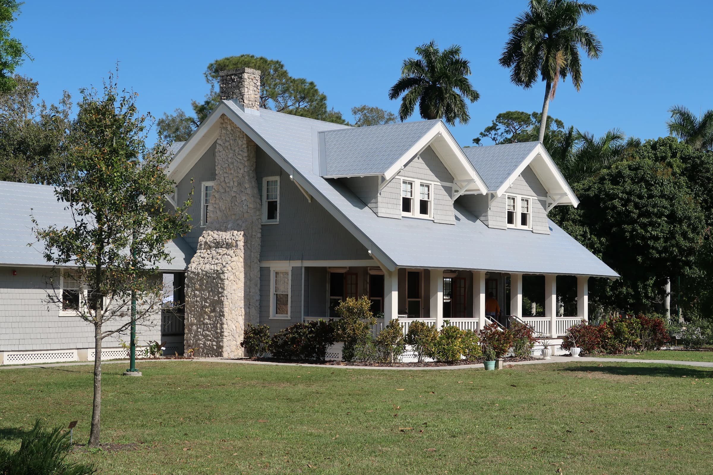 White whitewashed house under strong sun, with low wall and shade cut on stone floor