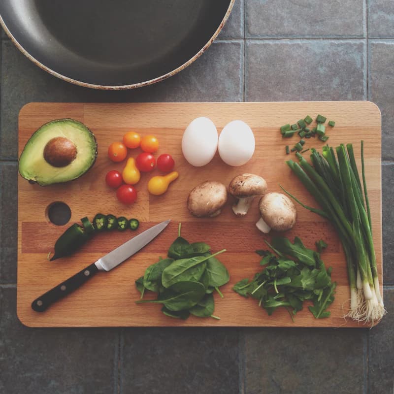 Hands jumping vegetables in a frying pan on the stove, with steam rising from the pan