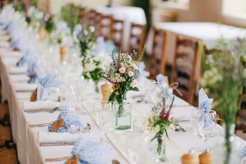 Long table placed outdoors for a wedding, with field flowers and linen napkins