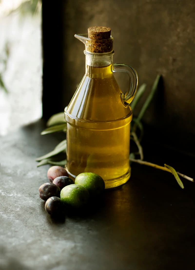 Bottle of olive oil with fresh olives and olive leaves