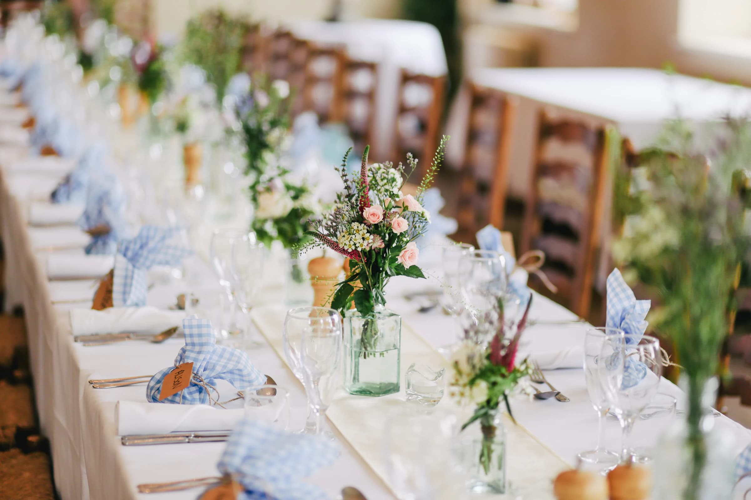 Long table placed outdoors for a wedding, with field flowers and linen napkins