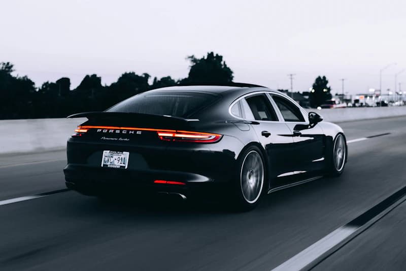 Black sports car parked facing the camera, facing a clear wall